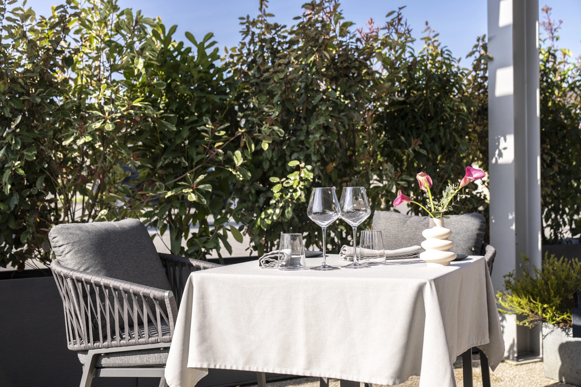Table pour deux sous la pergola de la terrasse de l'Auberge d'Arthaz, végétation verte et lumière de midi