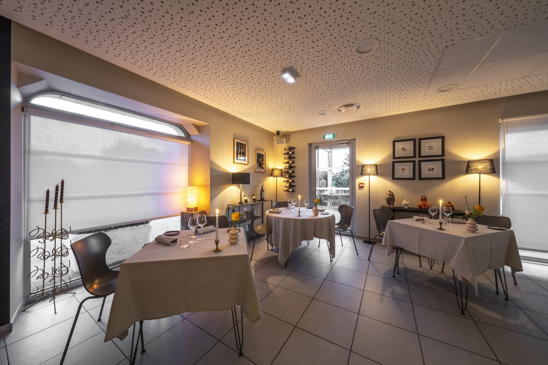 Salle secondaire de l'Auberge d'Arthaz avec fenêtre en arc, tables dressées et lumières chaudes pour le soir