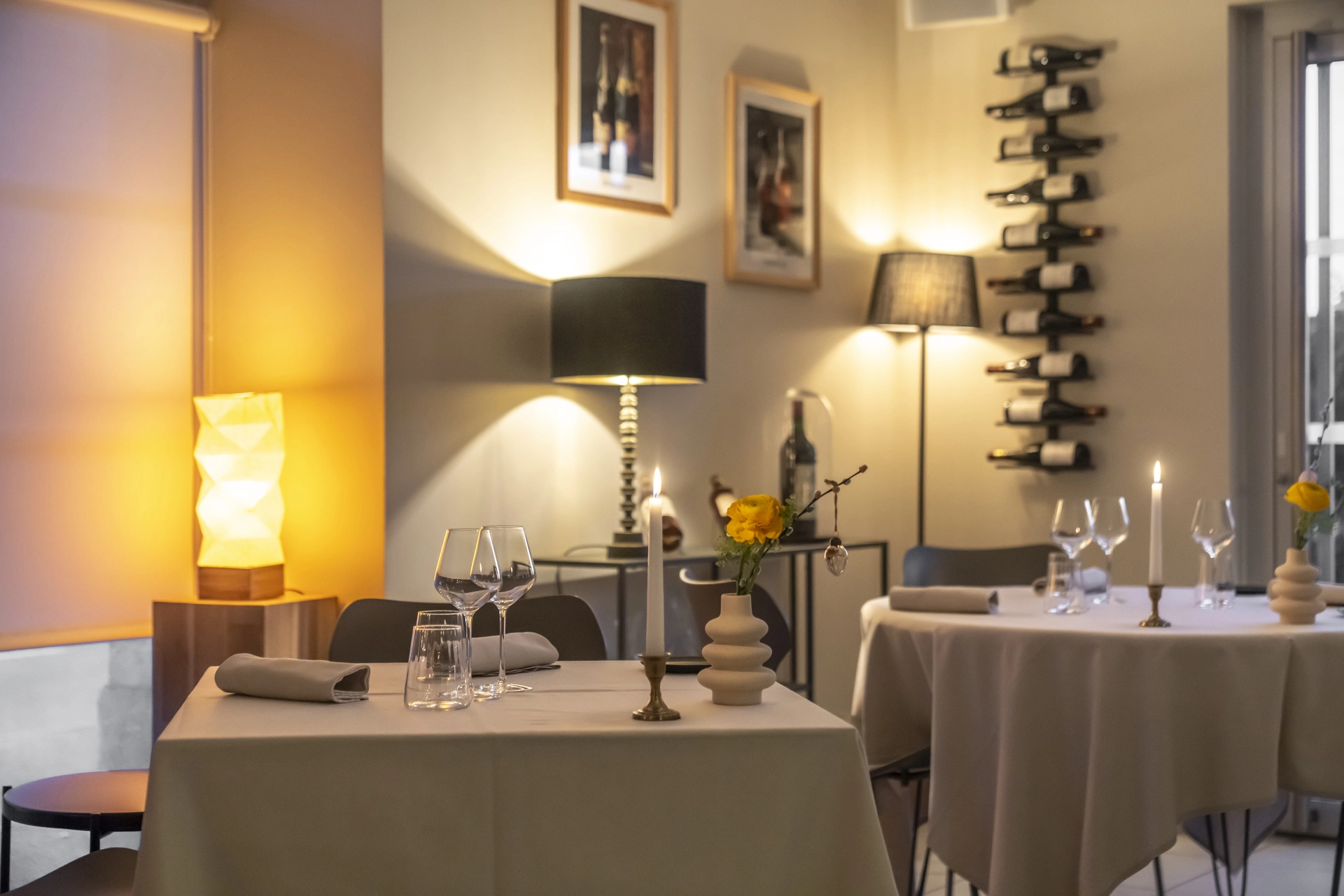 Salle principale de l'Auberge d'Arthaz en soirée, tables nappes blanches et casier à bouteilles éclairé