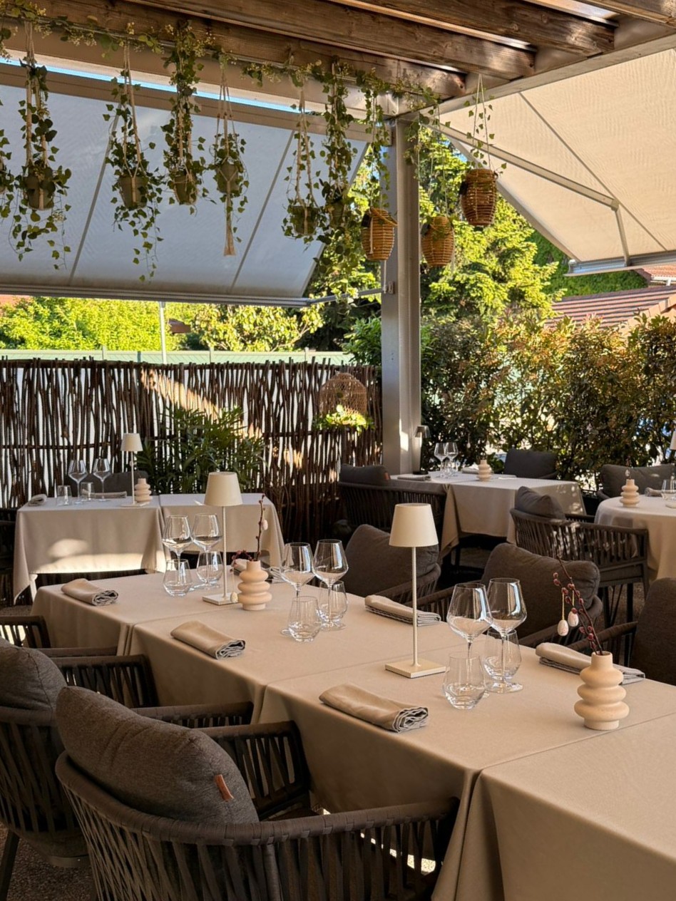 Tables dressées en enfilade sous la pergola bois de la terrasse de l'Auberge d'Arthaz, végétation et lumière naturelle